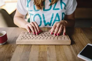 女性手在无线木质键盘上打字的特写