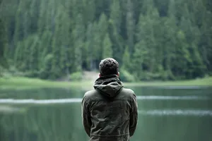 一名男子在水体前穿着连帽夹克的照片