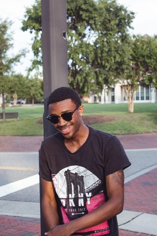 男子斜靠金属柱微笑