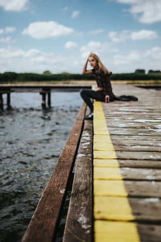 湖边一个木码头上美丽的金发女人
