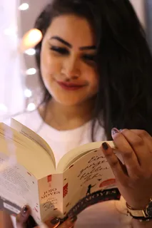 穿着白色圆领衬衫拿着Jojo Moyes书的女人