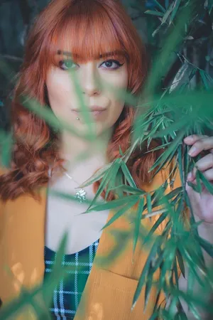 身穿黄色西装外套、手持绿色竹叶的女子