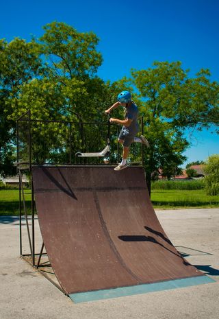 在棕色木制滑板坡道上玩滑板车的男子