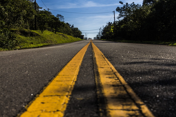 在白云下的绿树和蓝天之间的道路
