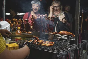 人们看着烤肉做饭