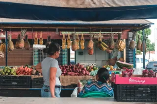 两名妇女面对水果和蔬菜摊位