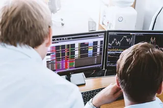 股票经纪人在多个电脑屏幕上查看图表、指数和数字