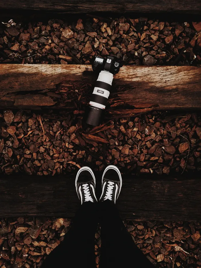 穿着黑白 Vans 低帮运动鞋的人站在黑色单反相机前