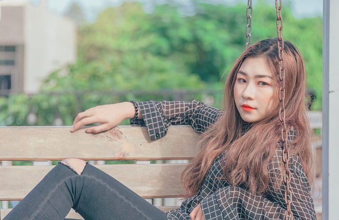 穿着黑色纽扣长袖衬衫的女人坐在棕色的摇摆长椅上