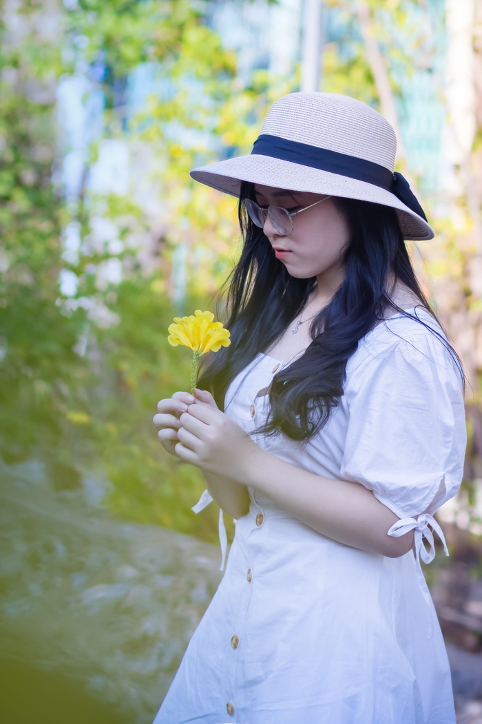 戴帽子戴眼镜拿着黄色花朵的女人
