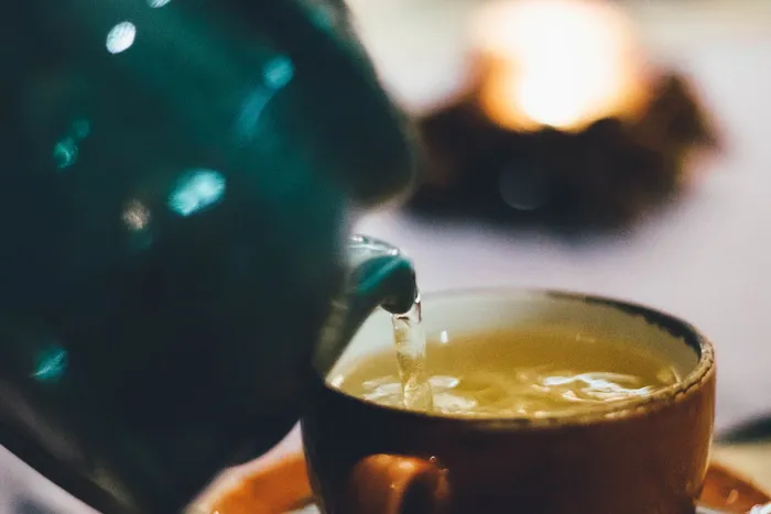 将液体倒入棕色陶瓷杯的人