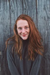 靠在木墙上微笑的女人