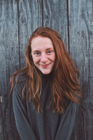 靠在木墙上微笑的女人