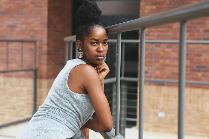 女人倚靠在灰色的金属框架上