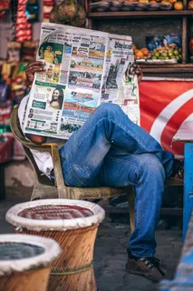 坐在塑料扶手椅上看报纸的男子