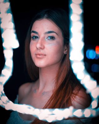 穿蓝绿色圆领上衣的女士，在细绳灯前