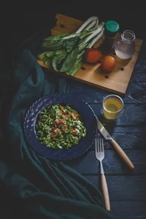 碗里的蔬菜沙拉，配有叉子、刀和玻璃