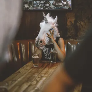 坐在桌子旁边的独角兽头的人 坐在桌子旁边的独角兽头的人