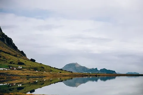 多云的日子里,映照在玻璃般的冰岛湖中的群山 多云的日子里,映照在玻璃般的冰岛湖中的群山