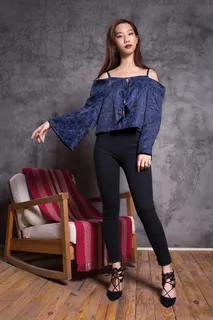 穿着蓝色露肩上衣的女人站在棕色木制摇椅旁