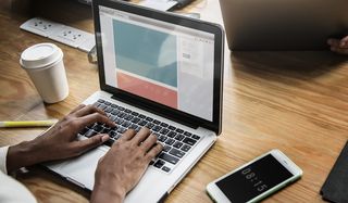 在棕色木桌上使用Macbook Pro的人