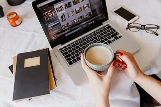 一位女士在一张桌子旁工作，桌上有一台笔记本电脑和一杯咖啡