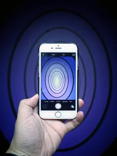 一个人用手机拍摄蓝色椭圆形的照片。