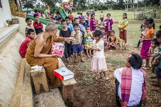僧侣在棕色混凝土建筑附近的孩子们面前