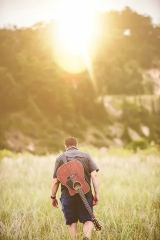 背上戴着切掉的吉他的男人走开的照片