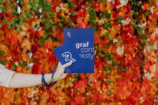 以五颜六色的树叶为背景，拿着格拉夫康夫书的女孩