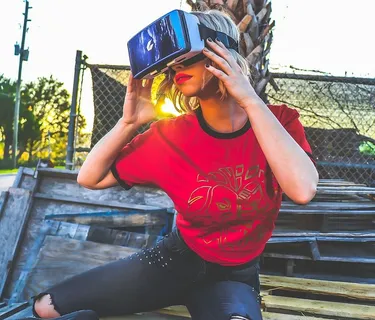 穿着红色和黑色上衣和蓝色旧底的女人戴着灰色和黑色的虚拟现实太阳镜 穿着红色和黑色上衣和蓝色旧底的女人戴着灰色和黑色的虚拟现实太阳镜