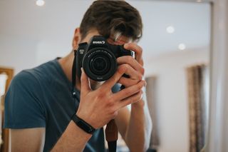 男子使用黑白佳能EOS单反相机