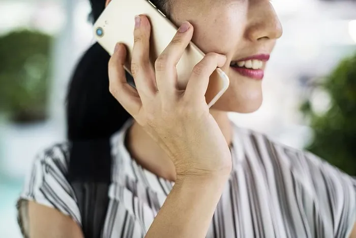 浅色对焦照片，微笑的女子手持金色Iphone 7