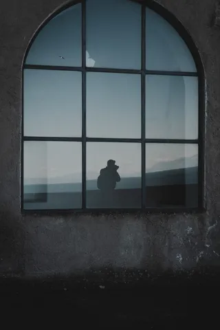 男子站在窗户旁的剪影照片