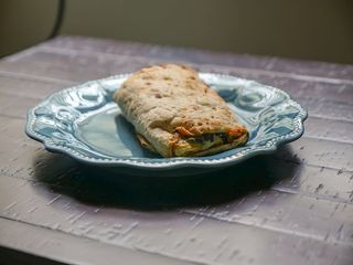 菠菜、羊奶干酪和鸡蛋都包在玉米饼里。坐在阳光下的蓝色盘子上。