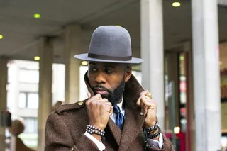 身穿棕色上衣、戴灰色帽子的男子