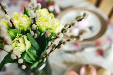 复活节餐桌上有可爱的粉色装饰、鲜花、柳絮和鸡蛋