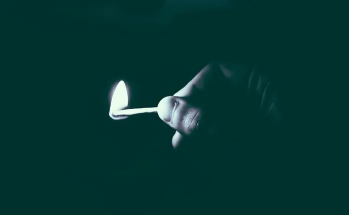 灰度照片，人物，手持，点燃，火柴棒，火，黑暗，夜晚