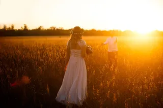 身穿白色连衣裙的女子在球场上手持花束