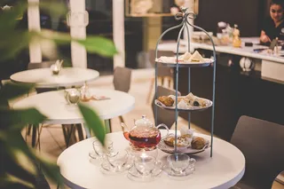 白色圆桌上灰色三层货架旁的茶具