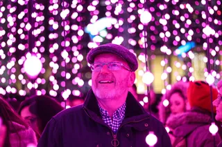 穿黑夹克的男人看着紫色的细绳灯