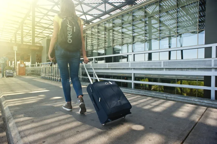一名女子一边在小路上散步一边搬运行李
