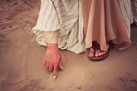 右手食指接触沙子的人