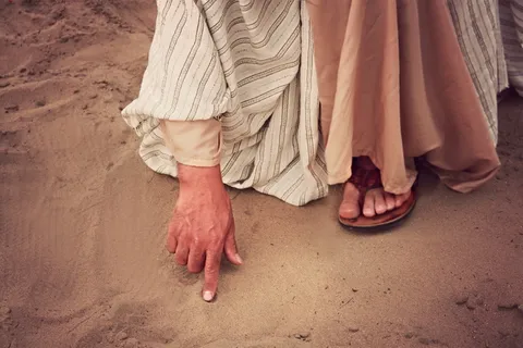 右手食指接触沙子的人