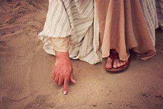 右手食指接触沙子的人