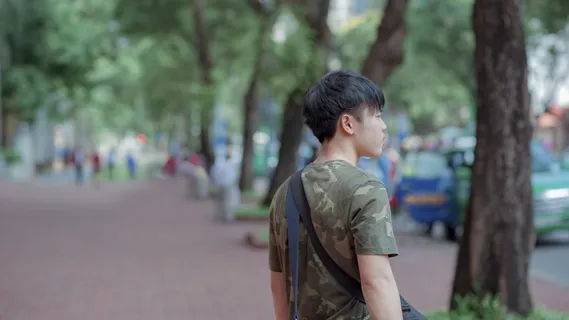 一名身穿绿灰色迷彩衫的男子站在树后