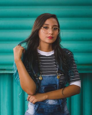 身穿工作服、戴眼镜的女子站在绿墙前