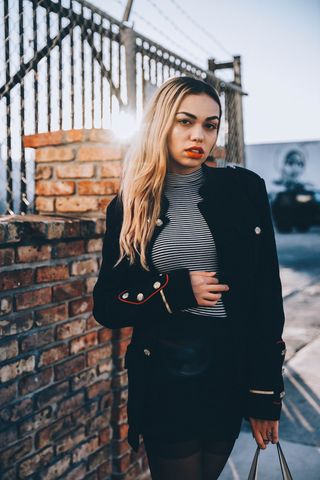 一个女人站在棕色的墙上，抱着她的肚子