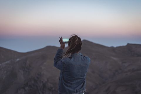 穿着蓝色牛仔夹克的女人拍摄山的照片 穿着蓝色牛仔夹克的女人拍摄山的照片