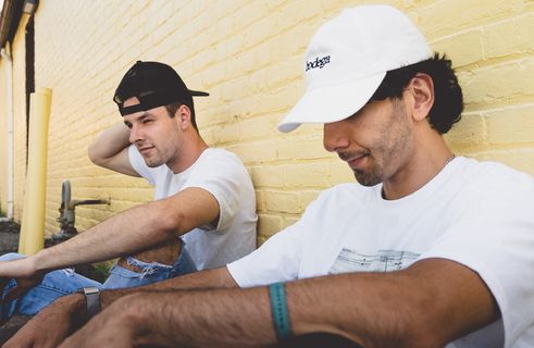 两名男子坐在米色混凝土墙旁